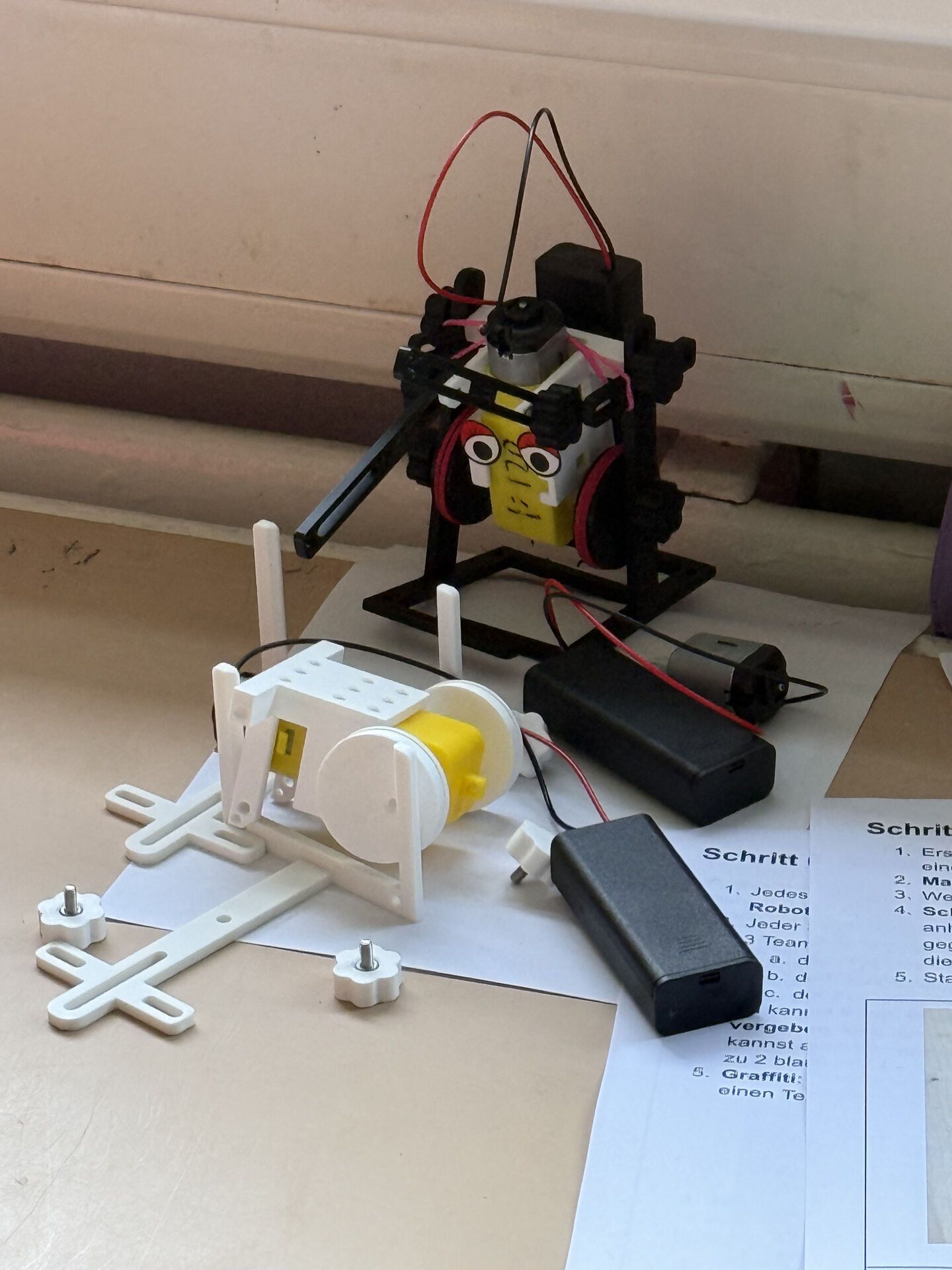 Robots in various stages of assembly next to a printed instruction sheet
