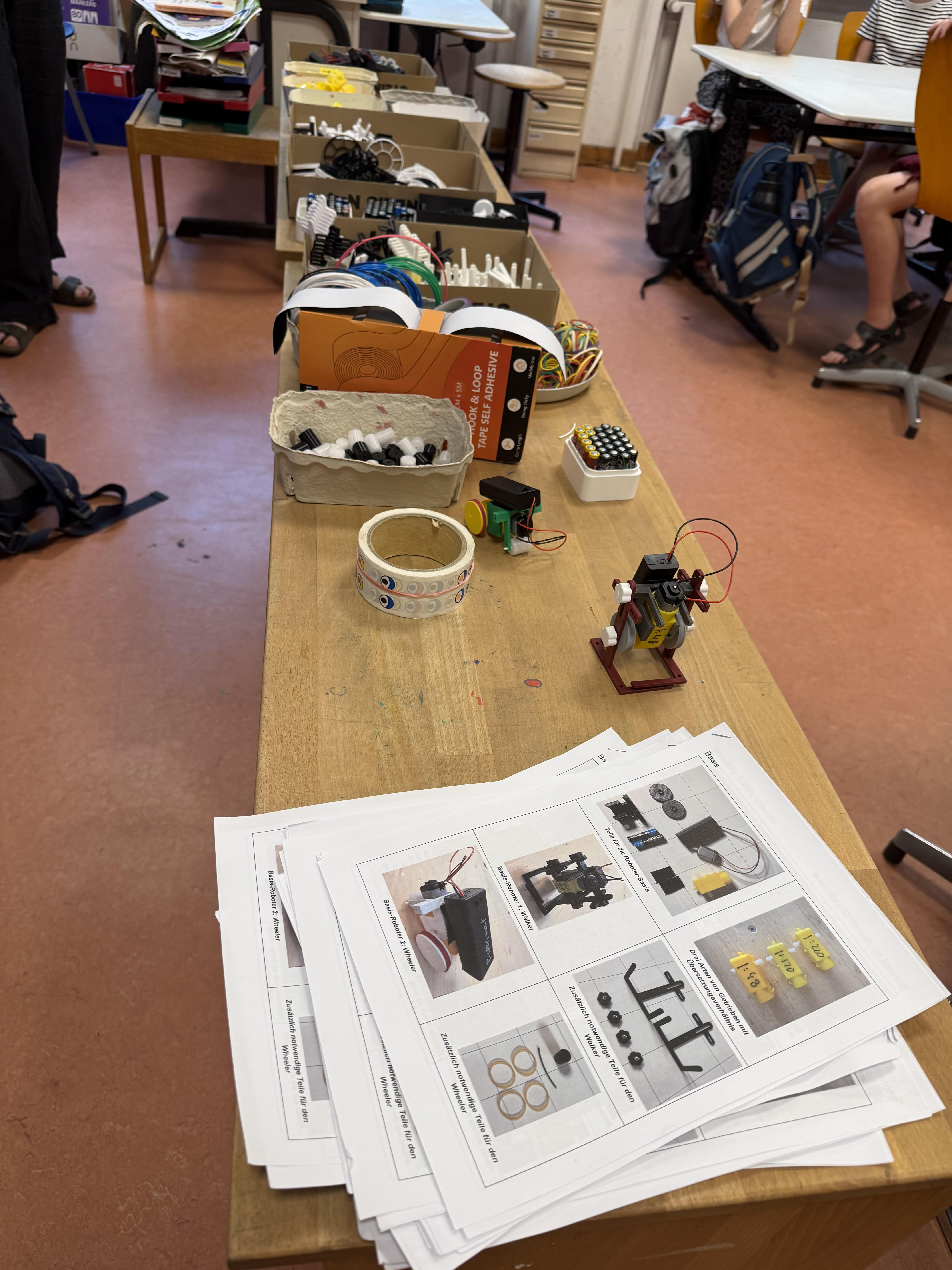 Workshop table with a half-built robot, pencil case and scattered parts