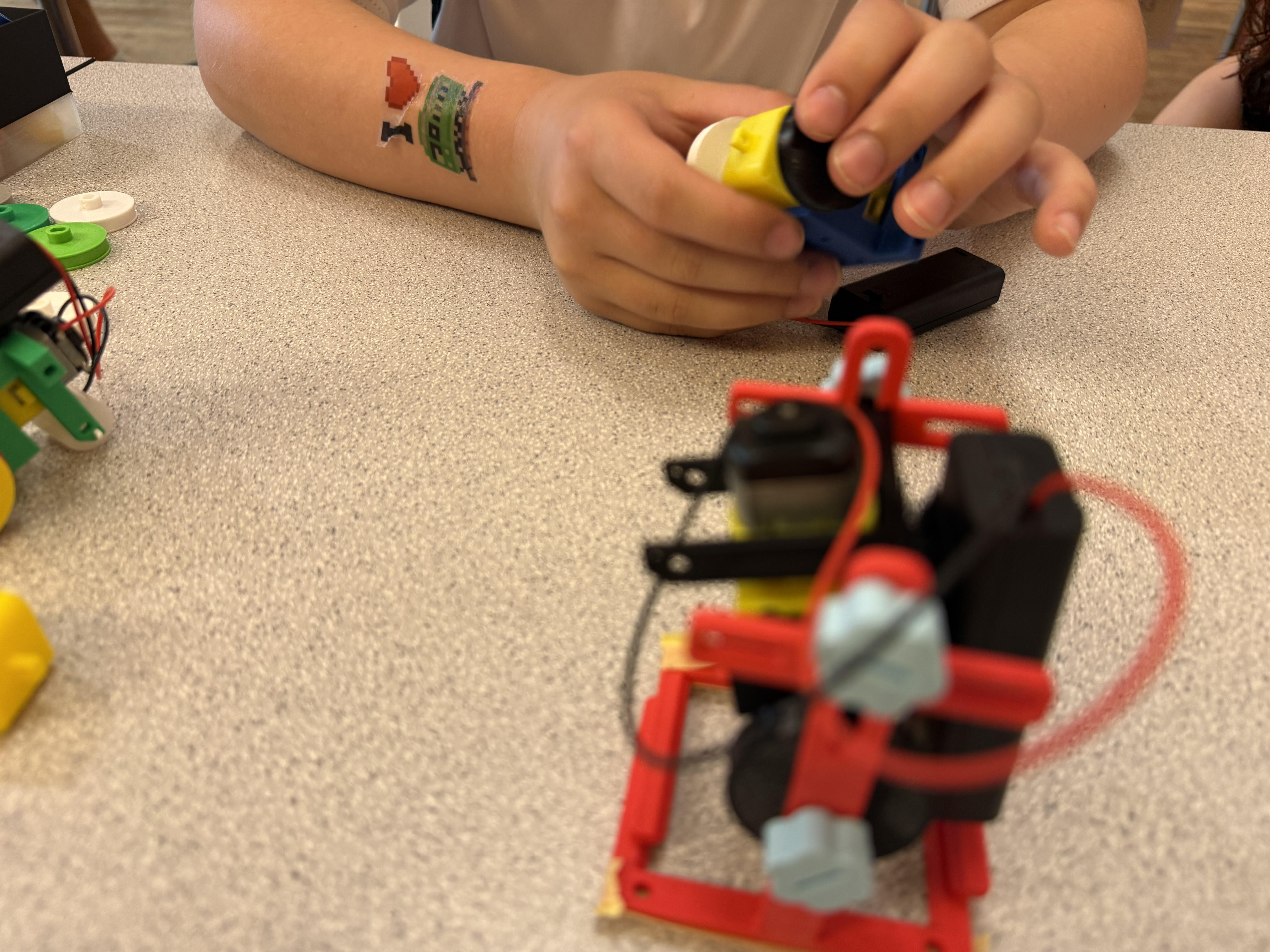A young maker customising a red robot with paint at the workbench